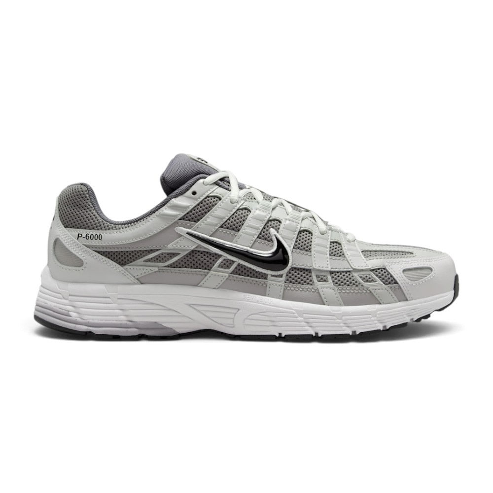 Highlights the early-2000s lateral silhouette featuring the Atmosphere Grey mesh upper, layered Vast Grey and silver leather lattice overlays, moulded synthetic leather Nike Swoosh with black outline, clean foam midsole, and black rubber outsole.