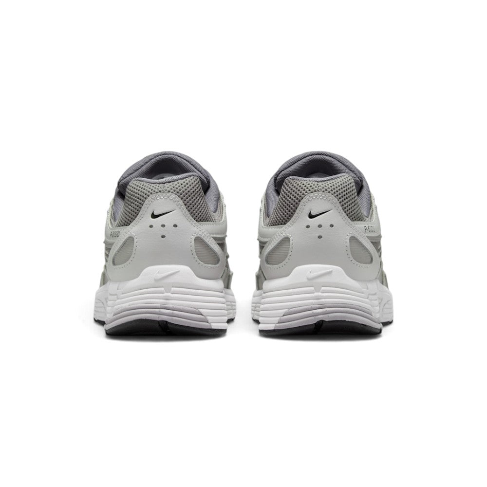 Focuses on the rear profile, displaying the structured Vast Grey synthetic heel counters, micro-Swooshes, ventilation perforations, and the wide base of the ribbed foam midsole.