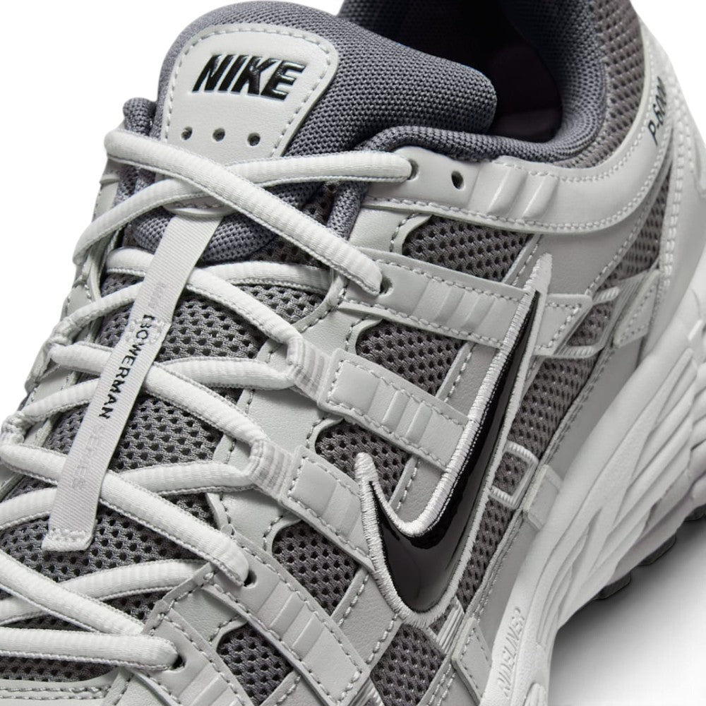 Details the micro-precision of the forefoot area, showing the open-weave Atmosphere Grey mesh toe box, synthetic leather toe cap, flat laces, and central tongue webbing strip.