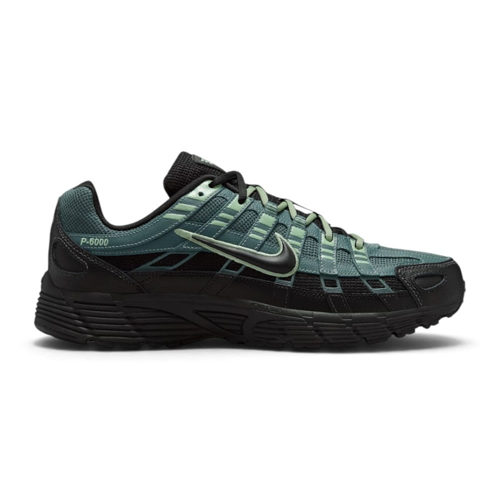 Highlights the early-2000s lateral silhouette featuring the Mineral Slate green mesh upper, layered black textured leather and Steam green cage overlays, moulded black Nike Swoosh with embroidered Steam trim, sculpted black foam midsole, and black rubber outsole.