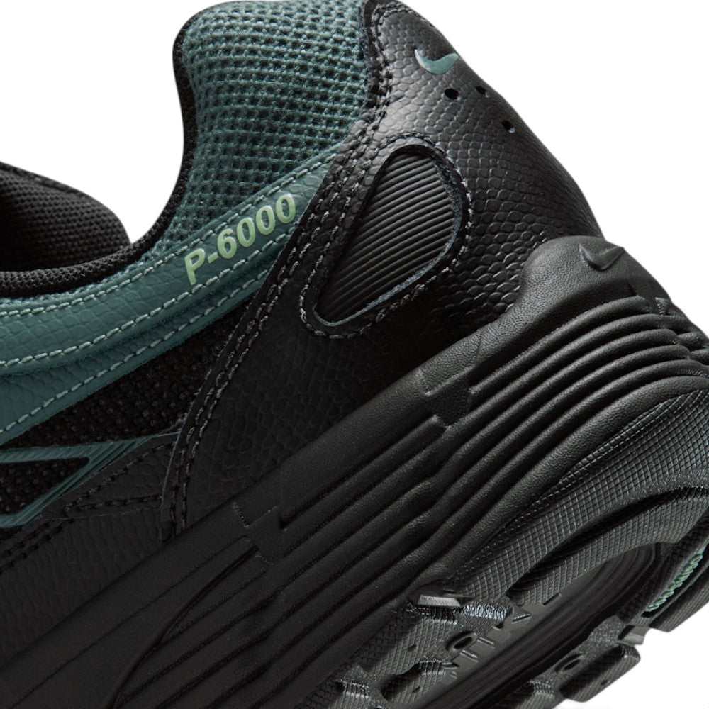 Highlights the "unreal" clean finish of the rear lateral tooling, showcasing the debossed "P-6000" collar script, textured heel panel, ribbed black foam midsole, and lugged rubber outsole tread.