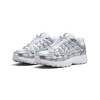 Emphasising the low-slung, athletic stance of the trainers and the high-shine reflective glow of the metallic silver leather panels against the crisp white base.