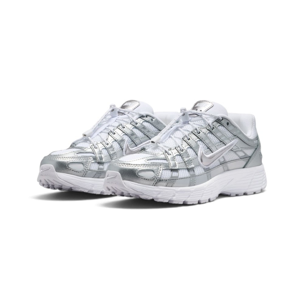 Emphasising the low-slung, athletic stance of the trainers and the high-shine reflective glow of the metallic silver leather panels against the crisp white base.