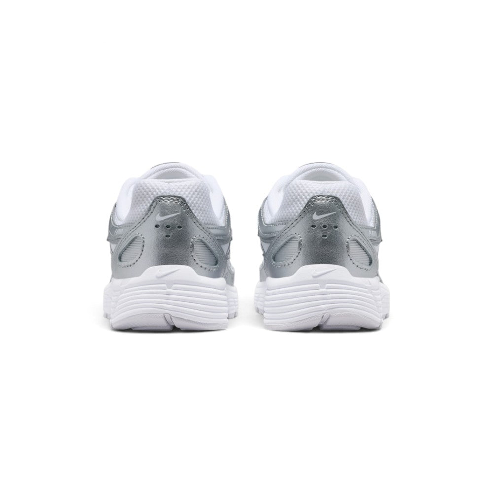 Focuses on the rear profile, highlighting the layered metallic silver heel counter, subtle Nike Swoosh logo, and the wide flared base of the white foam midsole.