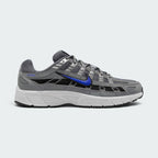 Highlights the lateral profile featuring a bold Racer Blue Nike Swoosh sweeping across the Smoke Grey mesh upper, structured Light Smoke Grey synthetic overlays, dark black underlay panels, and a clean white foam midsole.