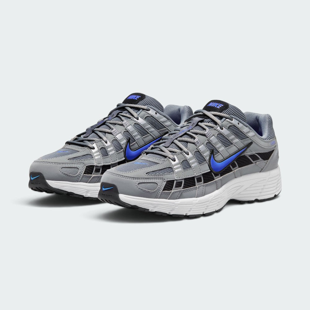 Emphasising the low-cut, athletic 2000s running stance of the trainers and the striking contrast between the neutral grey uppers and electric Racer Blue Swooshes.