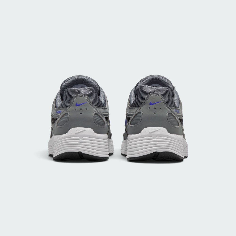 Focuses on the rear profile, highlighting the structured grey synthetic heel counters stamped with Racer Blue micro-Swooshes and blue "P-6000" branding, sitting above the wide white foam midsole base.