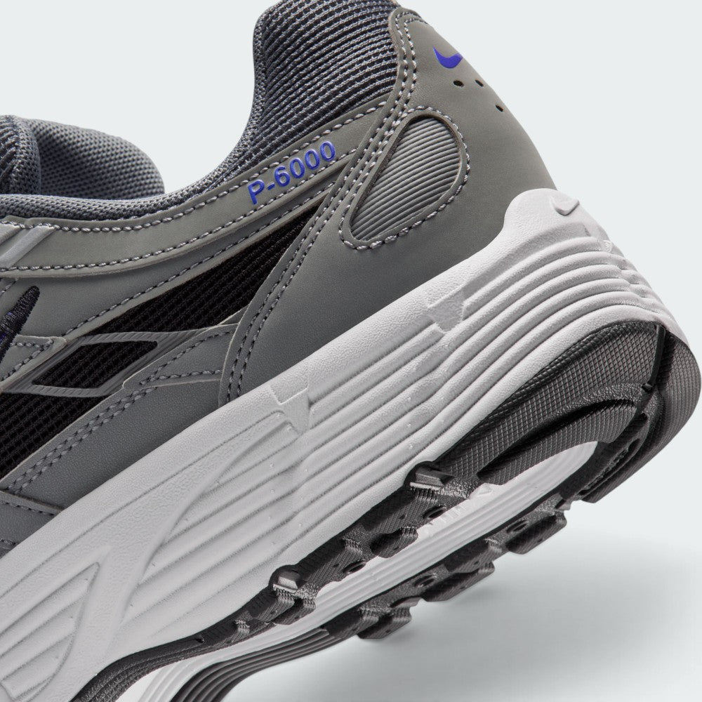 Highlights the "unreal" clean finish where the grooved white foam midsole carrier meets the textured black rubber outsole tread, framing the blue "P-6000" heel overlay badge.