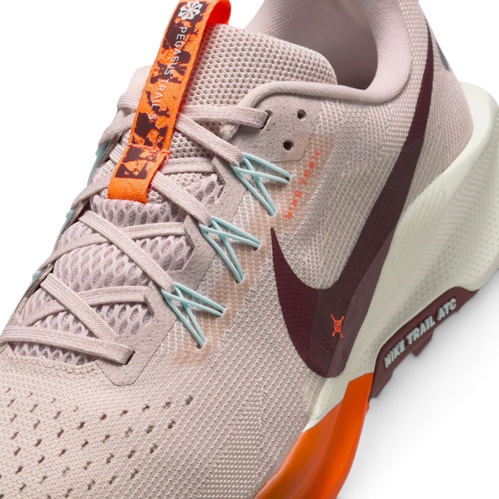 Details the micro-precision of the open-cell forefoot mesh upper, showing the laces, Silt Red suede eyestay overlay, orange floral tongue tab, and pale blue Flywire cables.