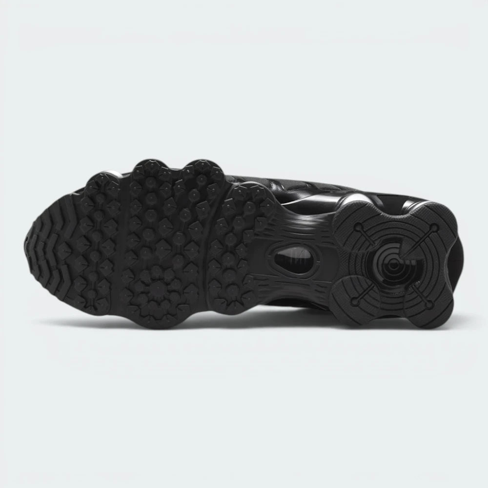 Displays the full-length black rubber sole, showcasing the circular tread pods below each Shox pillar engineered for unreal multi-surface traction and grip.