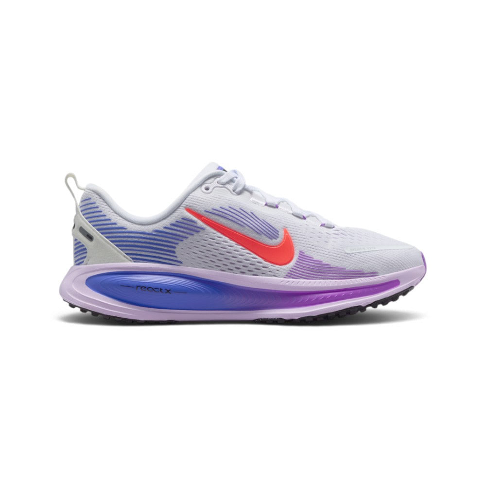 Highlights the lateral silhouette showing the white engineered mesh upper with purple haptic speed lines, raised Hot Lava Nike Swoosh, sculpted Violet Mist and Sapphire blue ReactX foam midsole with debossed "- reactx -" lettering, and black podular rubber outsole.