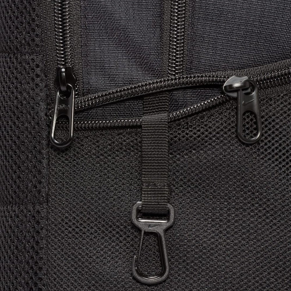 Trade Sports Nike Brasilia 9.5 backpack close-up showing black mesh pocket, zipper pulls, and gear attachment clip.
