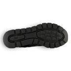 Full-length bottom profile showing the heavy-duty black rubber outsole, highlighting the pronounced trail-ready traction lugs, flex grooves for natural heel-to-toe roll, and embossed central New Balance branding.
