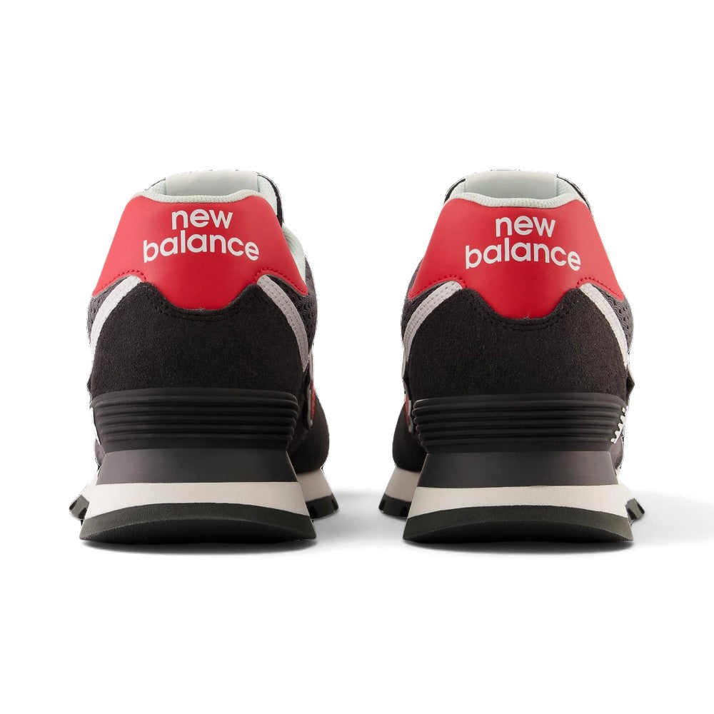 Close-up rear angle focusing on the supportive black suede heel wrap, bold red leather heel tab with white printed "new balance" typography, external TPU stabiliser clip, and flared rubber outsole rim.