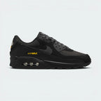 Highlights the high-velocity sweep of the crisp White Nike Swoosh, showing the professional, layered texture of the Black and Anthracite panels resting above the bold University Gold Max Air cassette window frame.