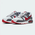 Showcases the full three-quarter athletic stance of the trainers, highlighting the harmonious blend of grey synthetic panels, breathable white mesh toe boxes, and the striking Gym Red leather accents running along the sides.