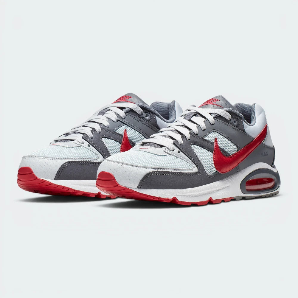 Showcases the full three-quarter athletic stance of the trainers, highlighting the harmonious blend of grey synthetic panels, breathable white mesh toe boxes, and the striking Gym Red leather accents running along the sides.