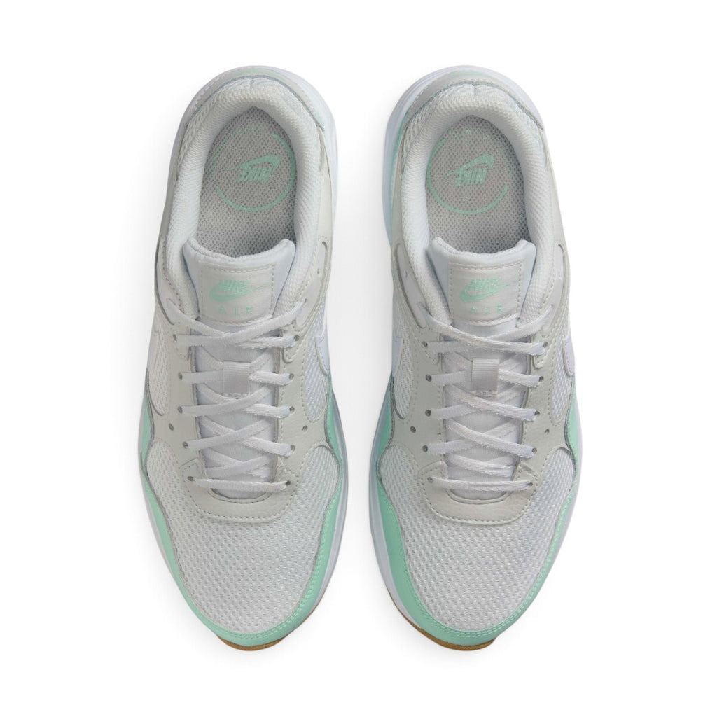 Overhead view looking down at the laced white running shoes, displaying the flat white laces, mint branding on the tongue labels, and the comfortable printed insoles.
