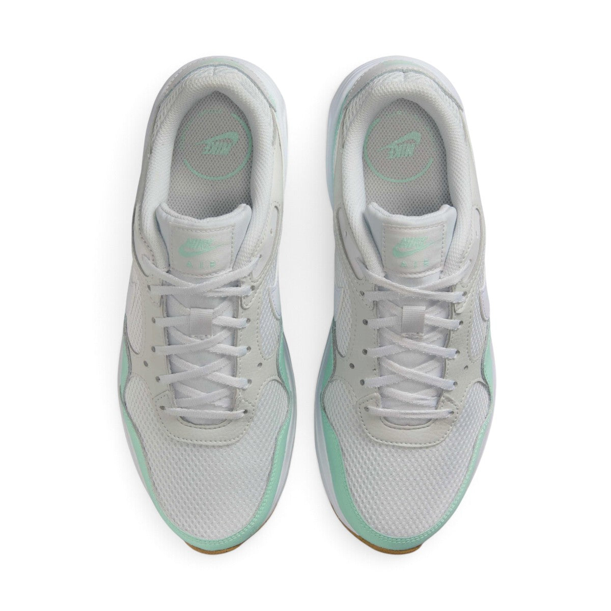 Overhead view looking down at the laced white running shoes, displaying the flat white laces, mint branding on the tongue labels, and the comfortable printed insoles.