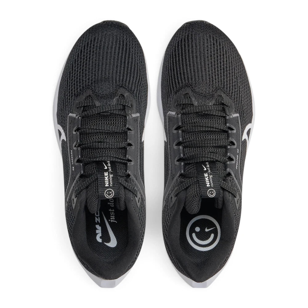 Overhead view looking down at the laced black running shoes, displaying the flat black laces, branded tongue tag featuring "nike running just do it", and the playful smiley graphic printed on the custom insoles.