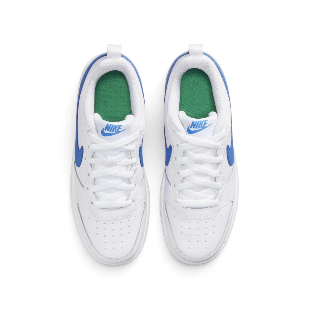 Focuses on the locked-in central lacing layout, displaying the crisp white laces, padded mesh tongue with blue printed Nike logo badge, cushioned Stadium Green insoles, and white heel pull tabs.