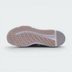 Displays the full-length rubber sole in pink and grey tones, featuring multi-directional flex grooves and a central white cavity exposing the foam cushioning core.