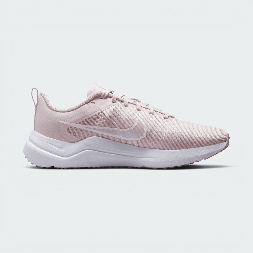 A light pink Nike running shoe with a white sole, shown in a side profile view against a light gray background.