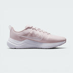 A light pink Nike running shoe with a white sole, shown in a side profile view against a light gray background.