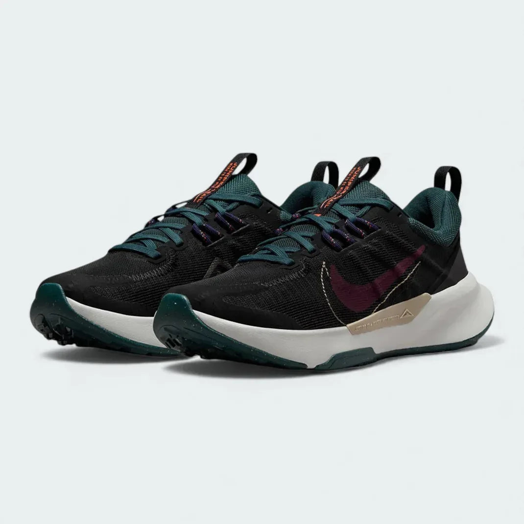 Angled view of two Nike Juniper Trail 2 Women's trail shoes in black and maroon, side by side, showcasing their robust design and athletic silhouette.