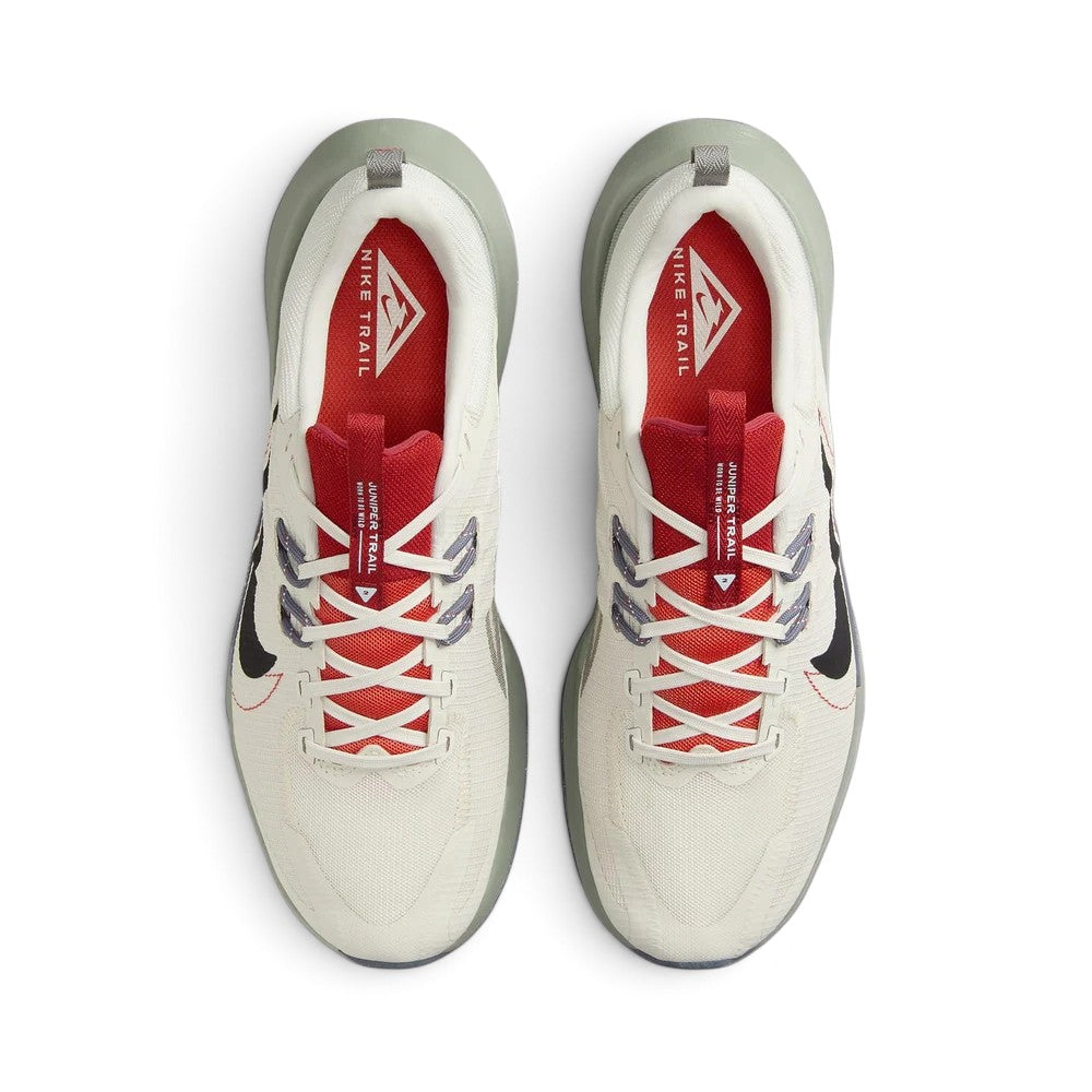 Focuses on the locked-in central lacing layout, displaying the vibrant red mesh tongues with white "JUNIPER TRAIL / WORN TO BE WILD" branded webbing strips, flecked Flywire cable anchors, off-white laces, and bright red insoles stamped with white Nike Trail logos.