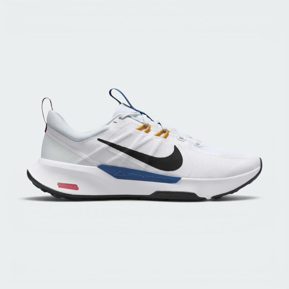 Highlights the lateral profile showing the black Nike Swoosh over white mesh, yellow flywire-style lace loops, deep ocean blue midsole clip with "JUST DO IT" messaging, and the painted red-and-white GR 11 trail marker on the heel foam.