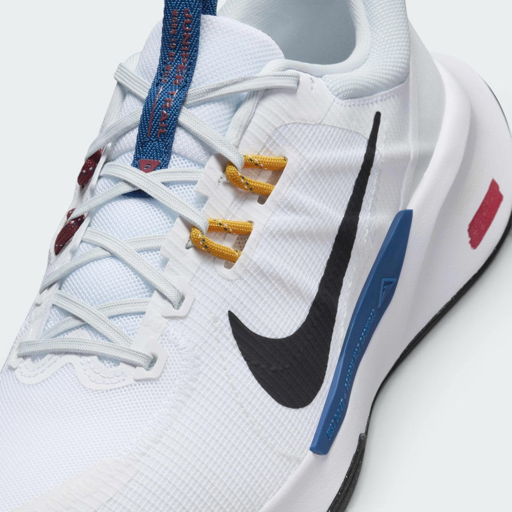 Details the micro-precision of the reinforced toe box, showing the blue "JUNIPER TRAIL" tongue tab, yellow lace loops, and white mesh ventilation matrix.