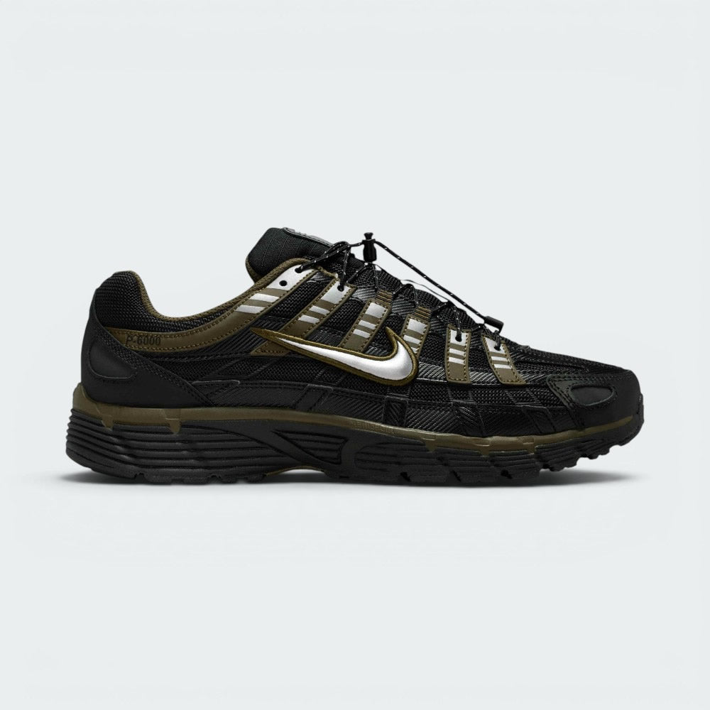 Highlights the lateral profile featuring a metallic silver Nike Swoosh with gold-khaki trim, showing the black mesh upper, olive-green Cargo Khaki overlays, silver reflective accents, speed-cord toggle lacing, and the dark foam midsole. Main image