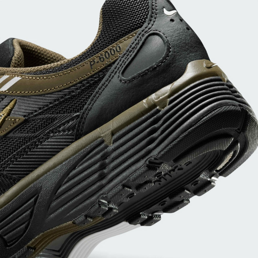 Highlights the "unreal" clean finish where the grooved dark foam midsole meets the black rubber outsole tread, displaying the debossed "P-6000" collar badge and olive heel clip.