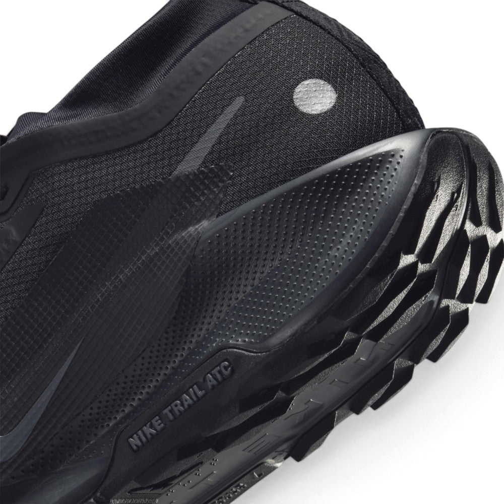 Macro view of the lateral heel transition, highlighting the textured ReactX foam sidewall wrap, reflective heel dot, and the aggressive profile of the all-terrain traction lug