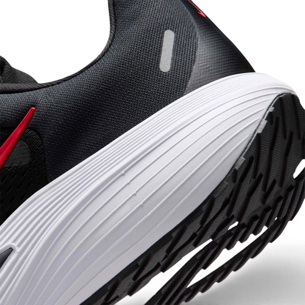 Close-up of a black athletic shoe showing the side heel area, featuring a thick white ribbed midsole, black outsole, and a small red accent near the collar.