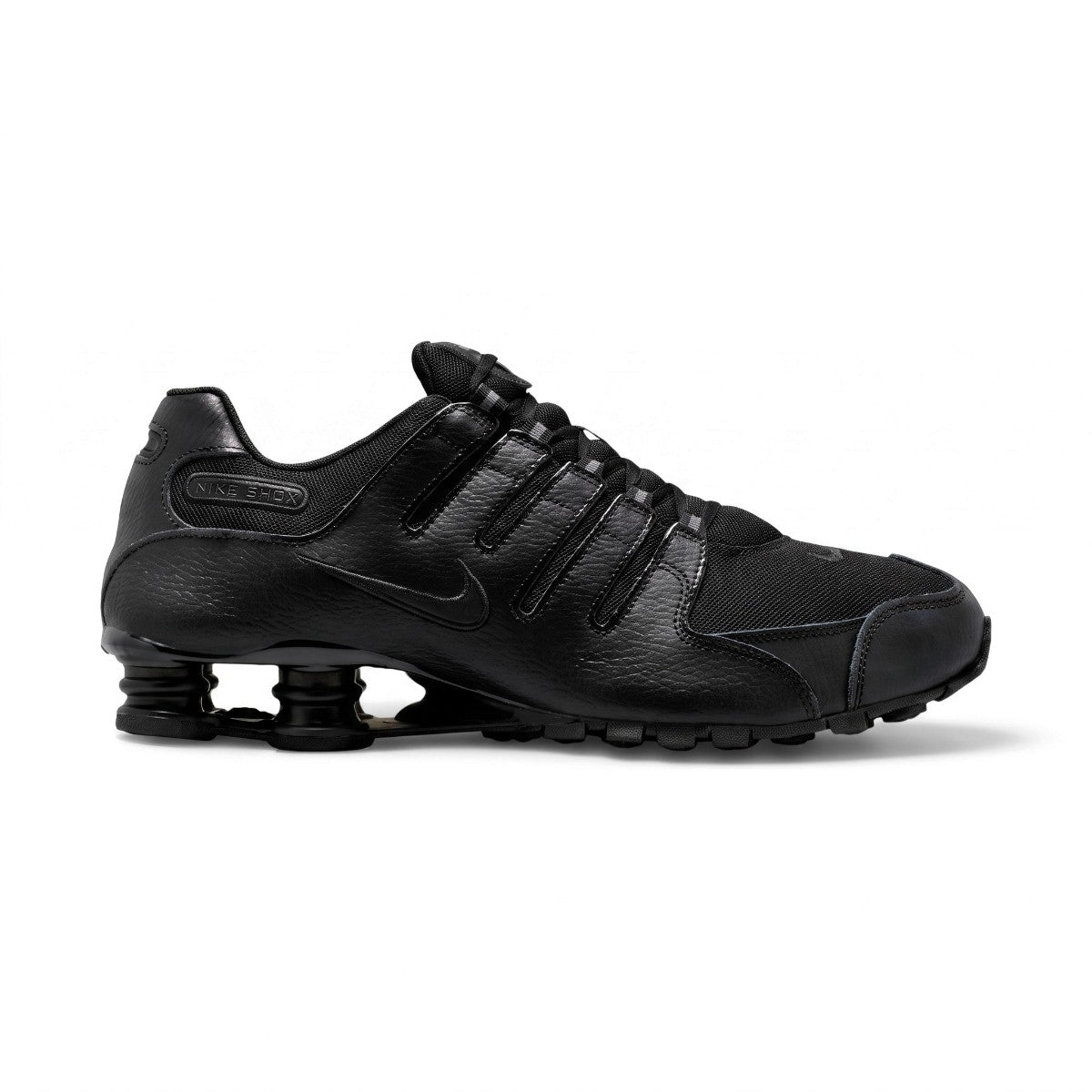 Studio lateral view of the Nike Shox NZ in all black, highlighting the synthetic leather and textile upper, ghillie lacing system, embossed Nike Shox badge, and black Shox cushioning columns in the heel. Main image