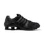 Studio lateral view of the Nike Shox NZ in all black, highlighting the synthetic leather and textile upper, ghillie lacing system, embossed Nike Shox badge, and black Shox cushioning columns in the heel.