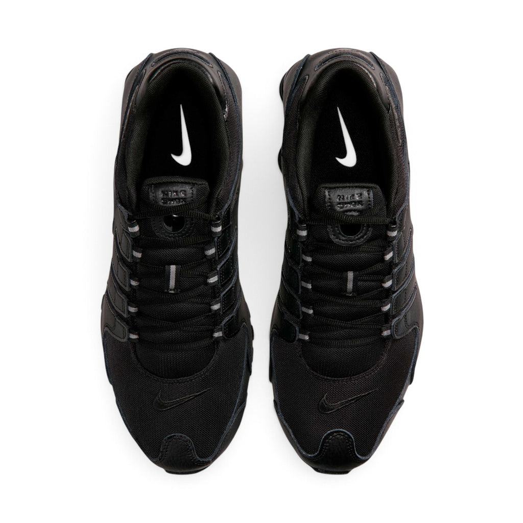 Bottom-down view of the black rubber outsole, showcasing the Waffle traction pattern, circular pod elements, and the central Shox bridge plate.