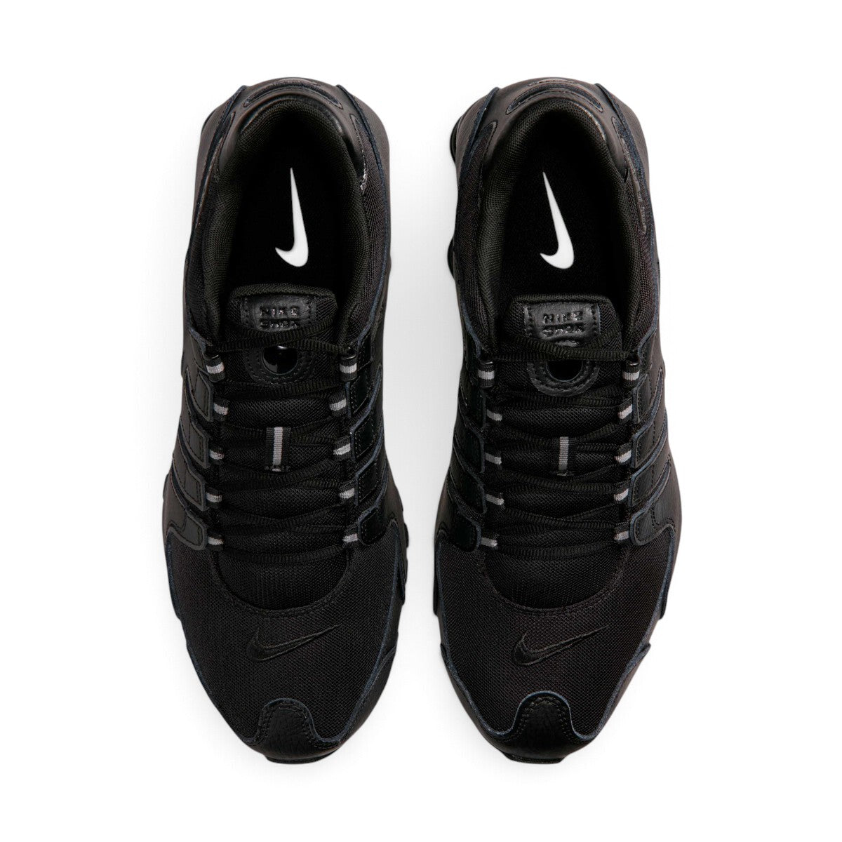 Bottom-down view of the black rubber outsole, showcasing the Waffle traction pattern, circular pod elements, and the central Shox bridge plate.