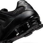 Detailed close-up angle capturing the embossed "NIKE SHOX" quarter branding, smooth leather heel panels, and the glossy finish of the springy Shox cushioning units.