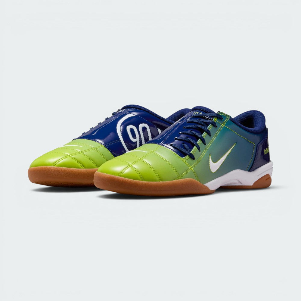 Emphasising the classic, aggressive athletic stance of the trainers and the striking contrast between the deep blue body and vibrant atomic green branding accents.