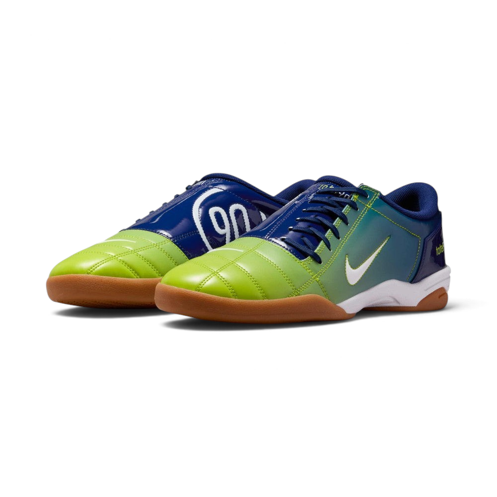 Emphasising the classic, aggressive athletic stance of the trainers and the striking contrast between the deep blue body and vibrant atomic green branding accents.