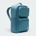 Highlights the high-velocity sweep of the comfortable padded shoulder straps, showing the professional, matte texture of the Smoky Blue woven polyester body and the modular zippered side utility pockets.