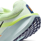 Close-up of a Nike running shoe showing the heel and midsole, featuring a light neon yellow-green mesh upper, a pale gray-green midsole, a dark navy outsole, and small orange accents.