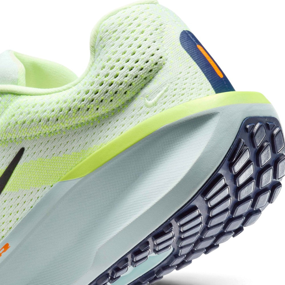 Close-up of a Nike running shoe showing the heel and midsole, featuring a light neon yellow-green mesh upper, a pale gray-green midsole, a dark navy outsole, and small orange accents.