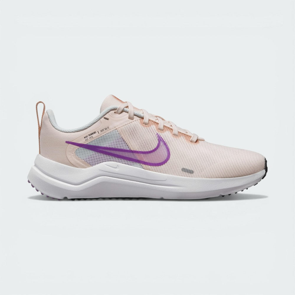 Side Profile Image: The Guava Ice Downshifter 12, highlighting the vibrant Rush Fuchsia Swoosh and the elevated foam midsole.