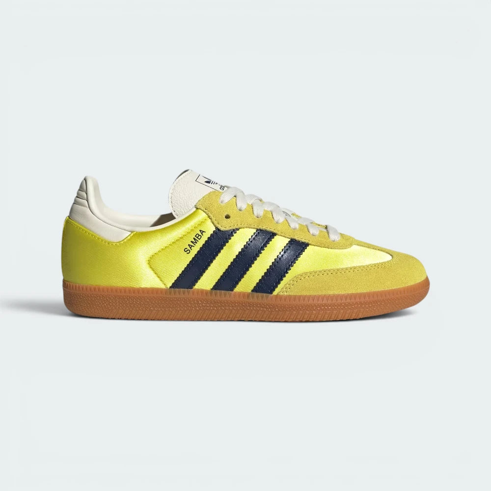 Highlights the high-velocity sweep of the Night Indigo serrated 3-Stripes and the professional, glistening textile depth of the Shock Yellow satin panels leading to the clean cream suede accents.
