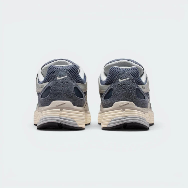 Focuses on the contoured shape of the padded low-cut collar, highlighting the reflective accents and the vertical leather overlay strip tracking down the rear spine.
