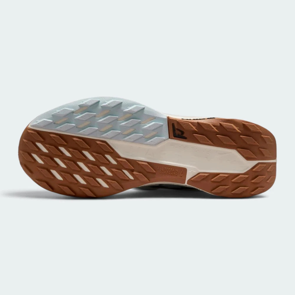 Displays the full-length Nike Trail All-Terrain Compound (ATC) rubber sole, showcasing the multi-directional lug grid and central stability shank with trail logo.